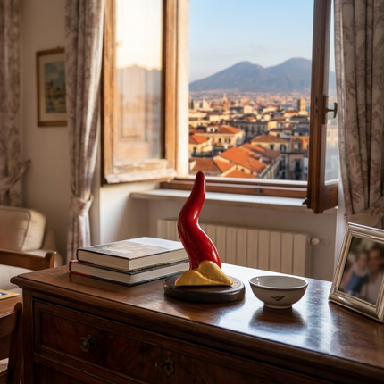 Scultura Corno Vesuvio in ceramica rossa e oro di Opere Partenopee posizionata su un mobile in salotto.